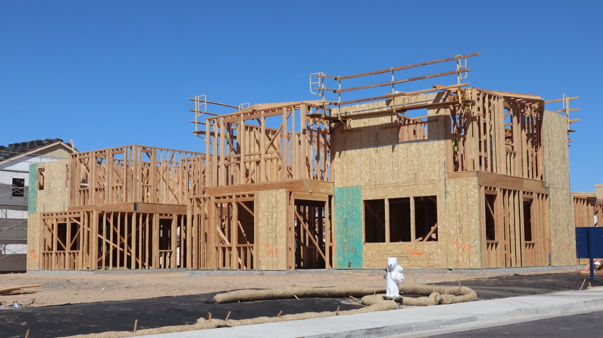Two-story new construction home mid-framing under a clear sky
