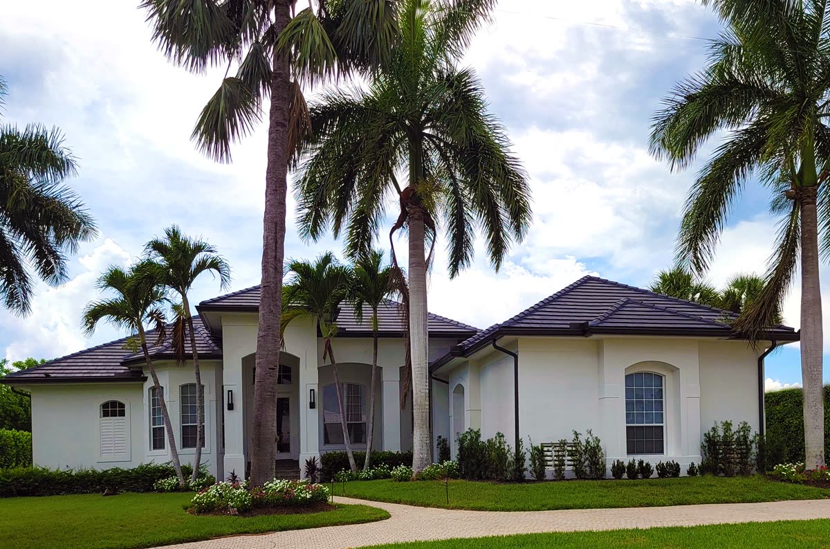 White stucco single-story Florida rental home surrounded by palm trees