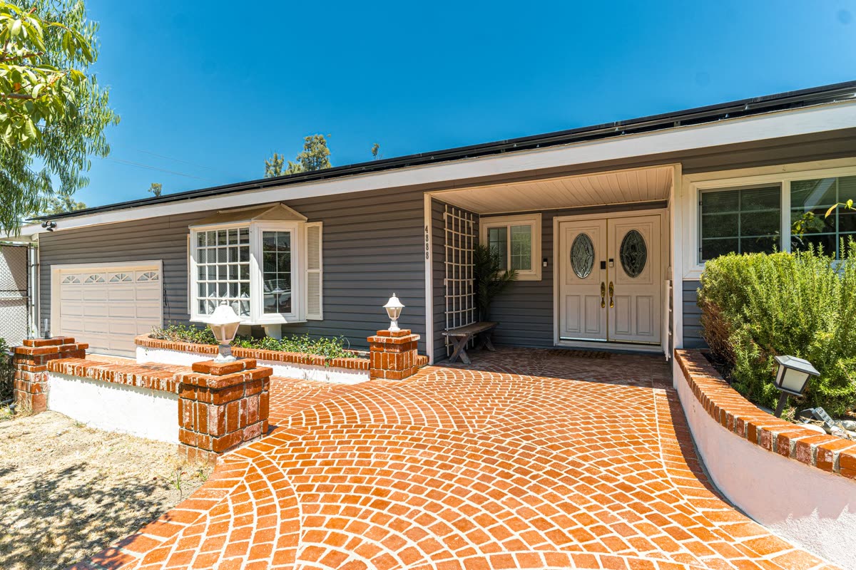 Renovated single-family ranch home exterior with brick driveway